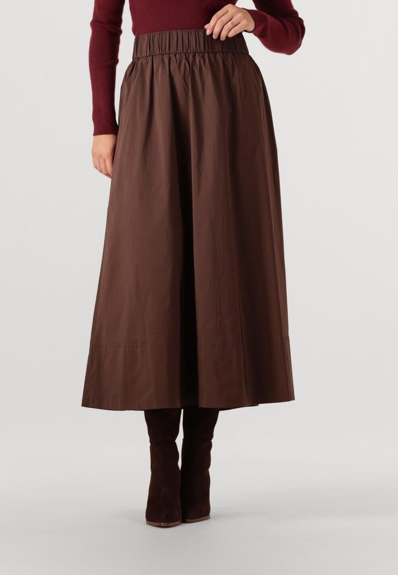 Bruine midi rok van gladde stof, met een elastische tailleband. Gecombineerd met bruin suède laarzen tot de knie. Netjes afgewerkte onderrand zonder patronen.
