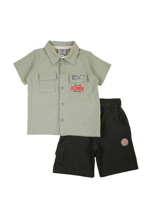 Chemise vert clair à manches courtes avec boutons et écussons, associée à un short noir avec une poche cargo et une taille élastique.