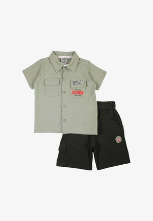 Chemise vert clair à manches courtes avec boutons et écussons, associée à un short noir avec une poche cargo et une taille élastique.