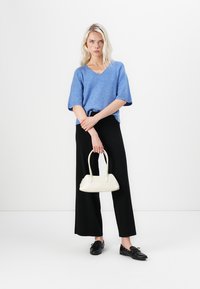 Blue short-sleeve V-neck sweater, black wide-leg pants, and a white handbag. Textured knit fabric, smooth bag surface, and minimalistic design.
