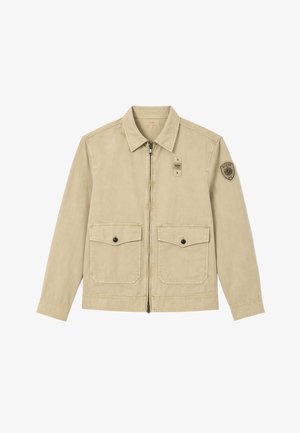 Giacca beige con zip, colletto appuntito, due tasche frontali con patta e bottoni e un patch logo circolare sulla parte superiore della manica sinistra.