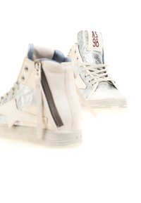 Tenisky s vysokým strihom, ktoré majú strieborný reflexný povrch, krémové akcenty, zips na boku a textúrovanú gumovú podrážku.