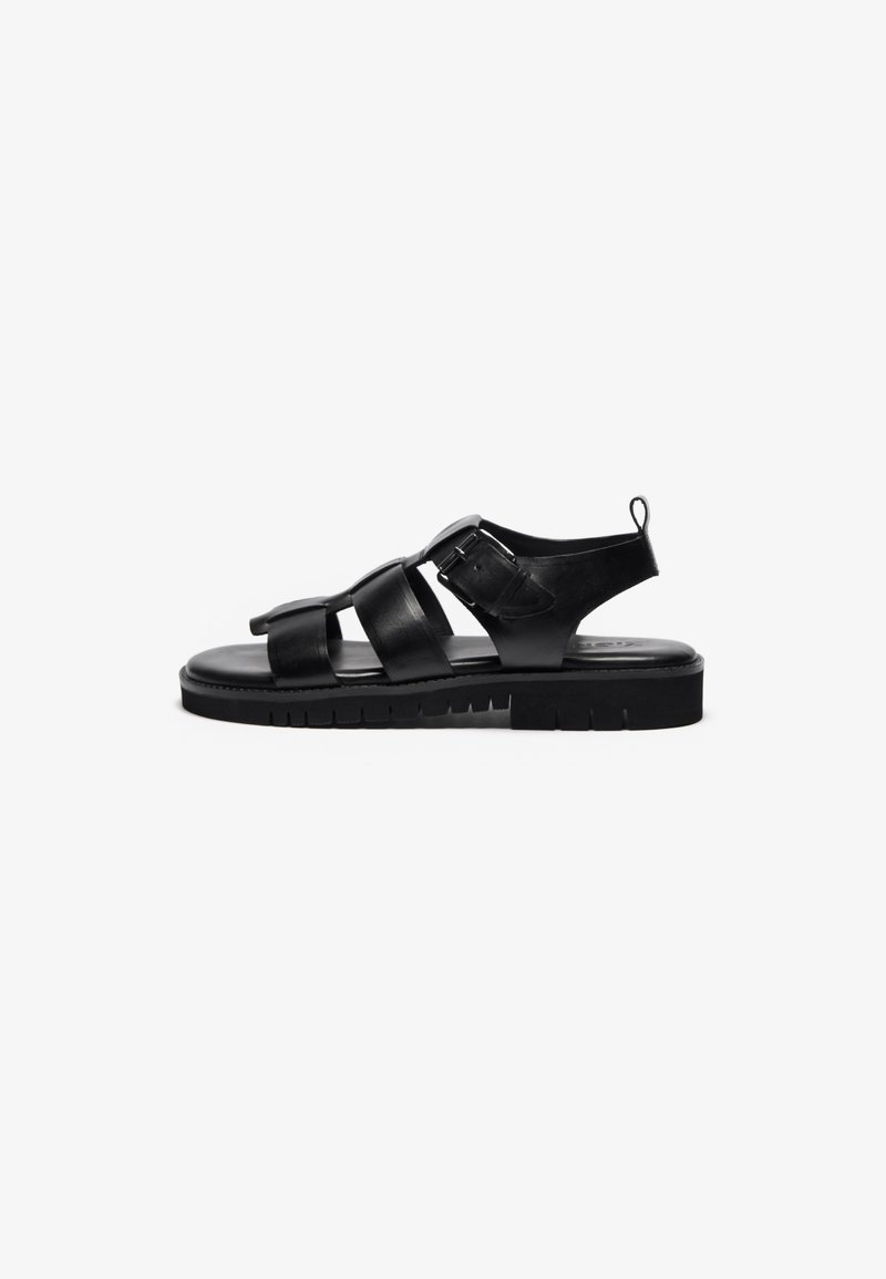 Black leather sandals with multiple straps, a buckle detail, flat sole, textured outsole, and a loop at the heel for easy wearing.