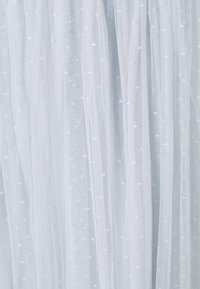 Tessuto di tulle azzurro chiaro con una texture trasparente, caratterizzato da pois bianchi sparsi su tutta la superficie. Materiale liscio e fluido con morbide pieghe.