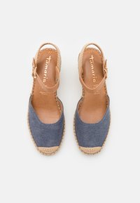 Espadrilles de tela azul con correa para el tobillo en color beige, suela de yute y punta redonda. El interior presenta un forro de cuero en tono beige claro.
