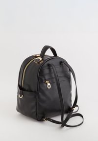 Czarny skórzany plecak o zaokrąglonym kształcie, z akcentami złotego sprzętu, przednią kieszenią na zamek, regulowanymi paskami i uchwytem u góry.