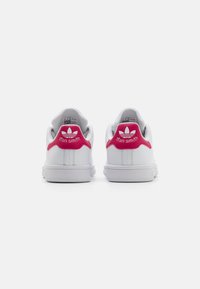 Vita l�ädersneakers med en rosa hälflik. Funktioner inkluderar "stan smith"-branding och tre-stripes-logga, gummisula, låg toppdesign.
