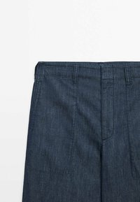 Dunkelblaue Jeans mit geradem Schnitt, sichtbaren Nähten, zwei Fronttaschen und einem Standardbund mit Gürtelschlaufen.