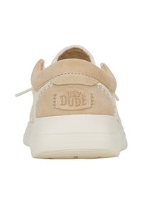 Beige suède instapschoen met witte stiksels en een trekbandje aan de achterkant. De zool is licht van kleur en met textuur, met het logo op de hak in relief.