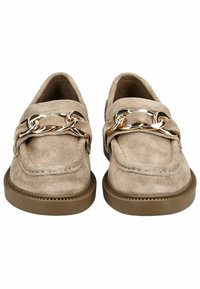 Mocasines de ante beige con punta redondeada, que cuentan con un acento de cadena dorada en la parte superior y una suela de goma marrón gruesa.