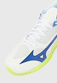 Λευκό αθλητικό παπούτσι με επάνω μέρος από δίχτυ με μπλε και νέον κίτρινες λεπτομέρειες, υφασμένη σόλα και παραδοσιακό κλείσιμο με κορδόνια για εφαρμογή.