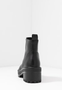 Black leather ankle boot with a chunky heel, smooth texture, and rear pull tab; features a ribbed sole for traction.