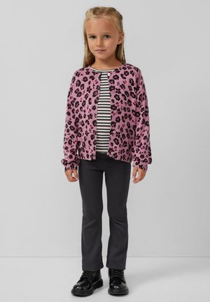 Roze luipaardprint cardigan over een zwart-wit gestreept shirt, gecombineerd met donkergrijze broek en glanzende zwarte laarzen.
