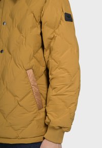 Giacca a vento gialla con design trapuntato, dotata di una tasca laterale in un finish satinato a contrasto e polsini a costine.