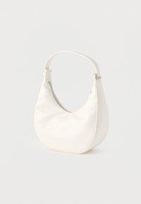 Μικρή λευκή τσάντα σε σχήμα ημισελήνου με έναν ιμάντα και κλείσιμο με φερμουάρ σε απλό φόντο.