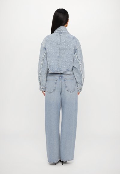 Svijetloplava traper jakna s kratkim dizajnom, teksturiranim rukavima i stršcima, kombinirana s laganim svijetloplavim trapericama širokog kroja.