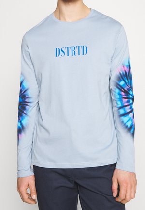 Helles blaues Langarm-T-Shirt aus Baumwolle, mit einem blauen "DSTRTD"-Logo und Batik-Elementen in Pink und Blau an den Ärmeln.
