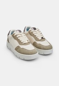 Sneakerid valge nahast ja heleda rohelise kummiga pealmise osaga. Omab paksu stringe, pehmendatud tallat ja metallilisi detaile keele peal.