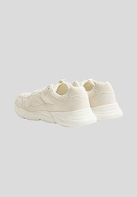 Białe trampki wykonane z mieszanki gładkich i fakturowanych materiałów, z grubą podeszwą, zaokrąglonym kształtem oraz subtelnymi akcentami na cholewce.