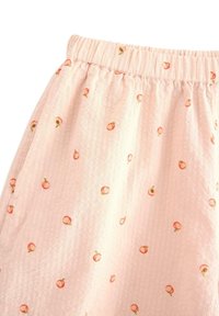 Ljust rosa, texturerad tyg med elastisk midja, som har små persikomotiv i orange och grönt överallt.