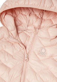 Polstrovaná růžová vesta se zipovým zapínáním a kapucí. Obsahuje vzor diamantového prošívání a malé vyšívané logo na hrudi. Hladká textura.