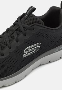 Czarne buty sportowe z teksturowaną siateczką na cholewce, z szarym podbiciem i srebrnym logo na boku. Sznurowanie z wyściełanym kołnierzem.