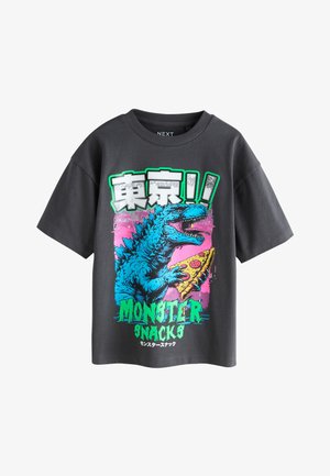 Sort kortærmet T-shirt med grafik af et blåt monster, der holder et pizzastykke og tekst på engelsk og japansk.