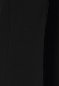 Černá látka s hladkou, matnou texturou; má jednoduchý, elegantní design bez viditelných vzorů nebo hardware.