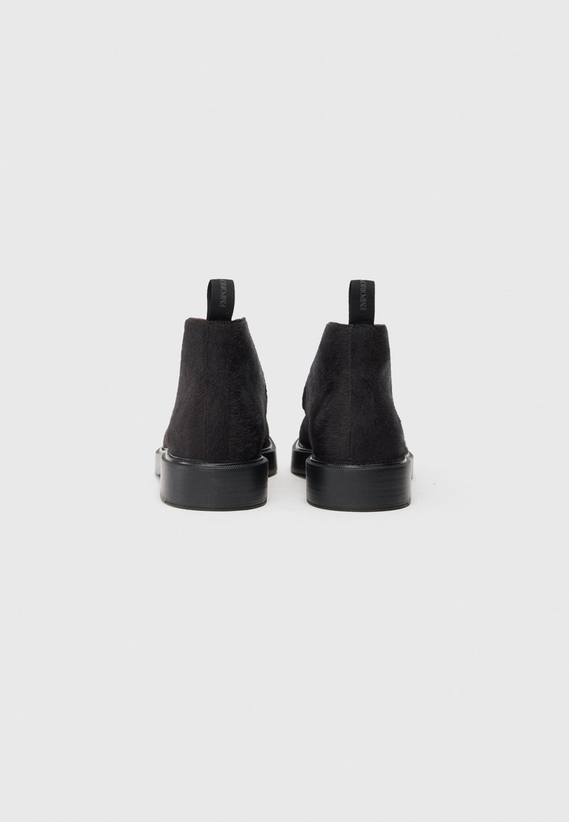 Sorte ruskind ankelstøvler med en glat overflade, rund tå og robust sort gummisål. Har en løbende producent for nem påtagning.