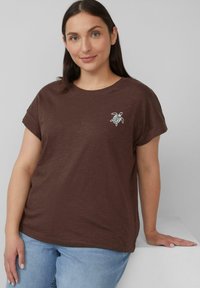 Roodbruin t-shirt met korte mouwen en een relaxte pasvorm, met een schildpaddendesign in witte en groene borduring op de linkerkant van de borst.