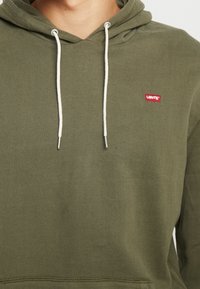 Sweat à capuche vert olive en mélange de coton doux, avec une poche avant, des cordons de serrage réglables et un petit logo Levi's rouge sur la poitrine.