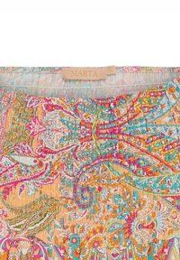 Farverigt blomstertrykstof i nuancer af pink, orange og turkis. Har en smocket tekstur og et vævet mærke med teksten "MARTA."