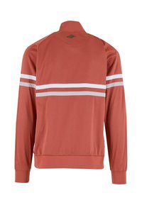 Rød atletisk jakke med høj krave og lange ærmer. Har to vandrette hvide og grå striber over ryggen. Glat, letvægtsstof.