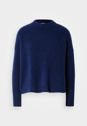 Navy blauwe gebreide trui met een hoge hals, verlaagde schouders en lange mouwen. Zachte textuur met een ontspannen, boxy pasvorm. Geen patronen of accenten.