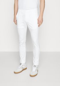 Witte broek van een katoenmengsel met een slanke pasvorm, voorzien van zijzakken en opgerolde boorden, gecombineerd met witte sneakers en een effen wit T-shirt.