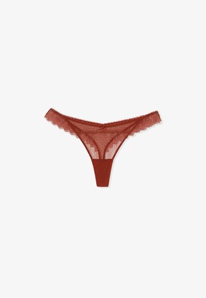 Czerwony koronkowy string damski z kwiatowymi wzorami, falbankowymi krawędziami i małą kokardką na środku pasa, prezentowany na białym tle.