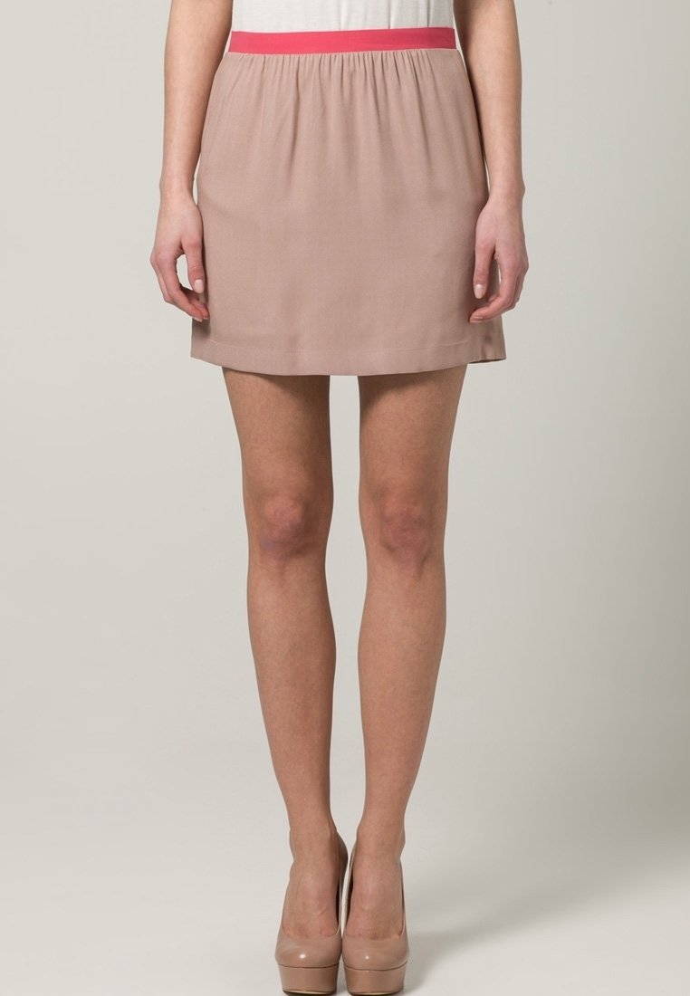 Falda con cinturilla rosa y tela de color beige claro, de textura suave, corte recto y diseño de altura media, combinada con tacones nude.