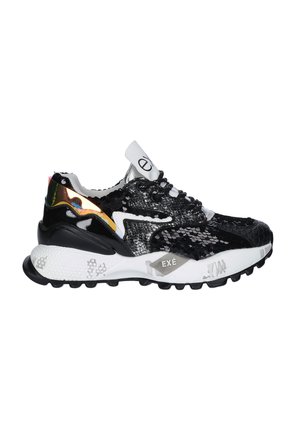 Zapatilla negra y blanca con lentejuelas, patrones texturizados, suela blanca gruesa con banda de rodadura negra y un detalle reflectante naranja en el lateral.