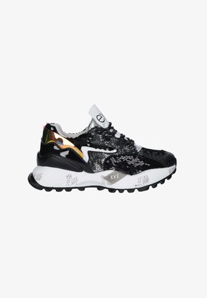 Zapatilla negra y blanca con lentejuelas, patrones texturizados, suela blanca gruesa con banda de rodadura negra y un detalle reflectante naranja en el lateral.