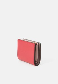 Portefeuille plié en cuir rouge texturé avec un intérieur beige clair contrastant et des accents marron foncé. Il comporte un compartiment zippé et des emplacements pour cartes.