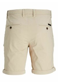 Shorts en coton beige avec une finition texturée, dotés de deux poches arrière avec boutons et de revers roulés. Conception simple avec des lignes épurées.