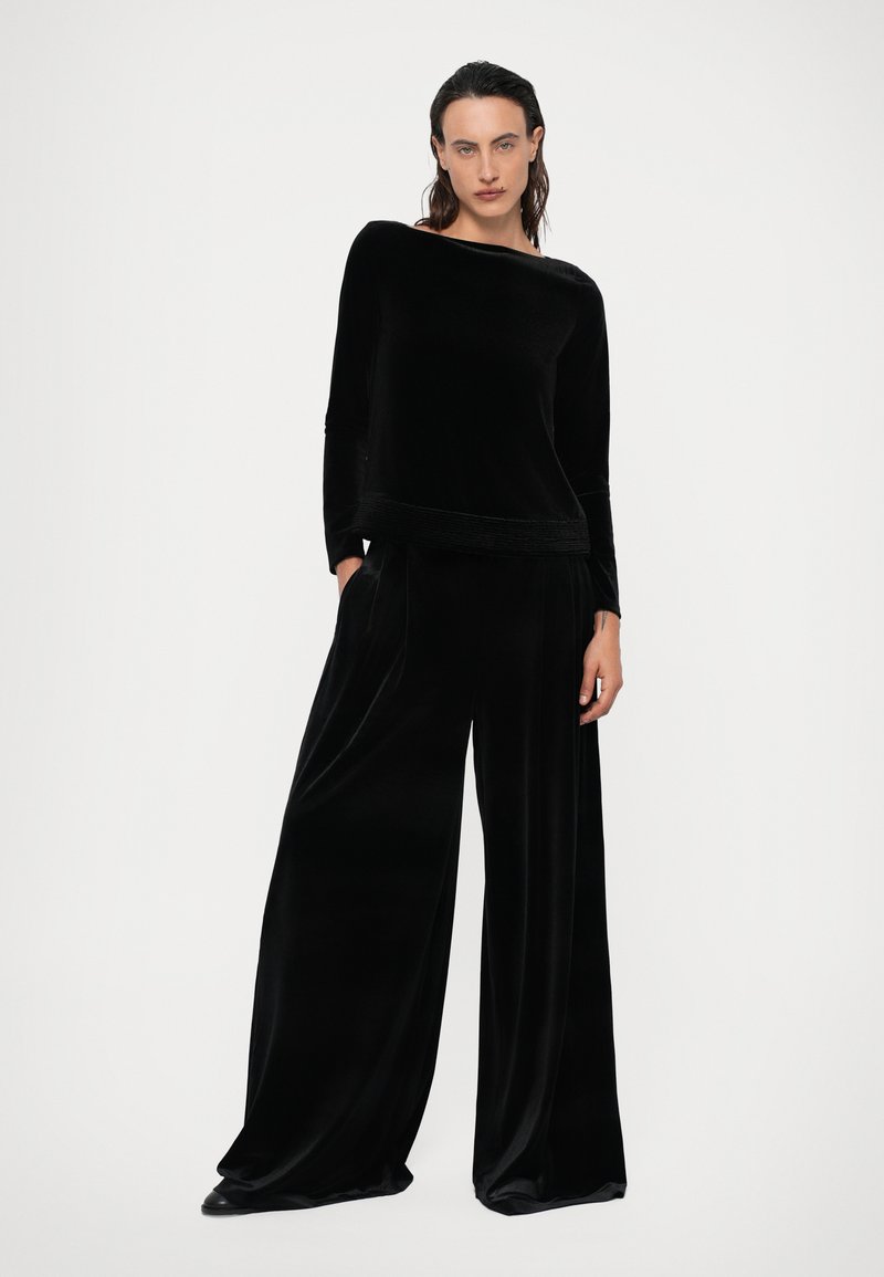 Black velvet ensemble featuring a long-sleeve top with a rounded neckline and wide-leg pants with a smooth texture and relaxed fit.
