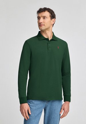 Donkergroene polo met lange mouwen, voorzien van een klassieke kraag, een drie-knopen placket en een rode logo-borduursel op de linkerborst.