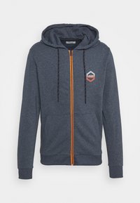 Navy zip-up hoodie with orange zipper and drawstrings, featuring a hexagonal logo on the chest. Soft fabric with a relaxed fit.