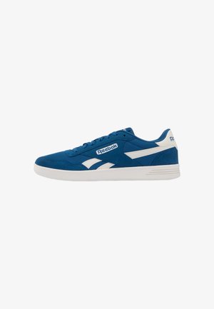 Blauwe en witte lage Reebok sneaker met veter aan de voorkant en witte zool, zijaanzicht op een witte achtergrond.