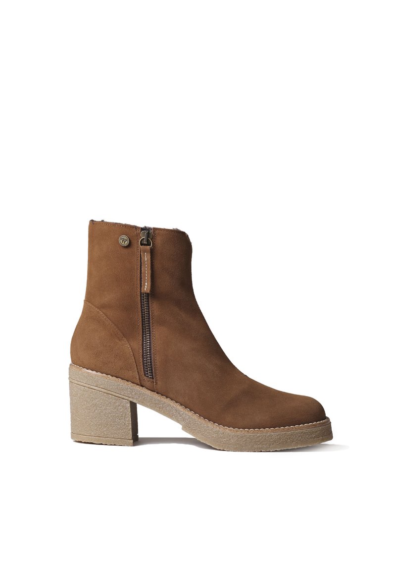 Stivaletto in suede marrone con chiusura zip, punta tonda e tacco spesso e texturizzato. Accentuato da una cucitura decorativa attorno alla suola.