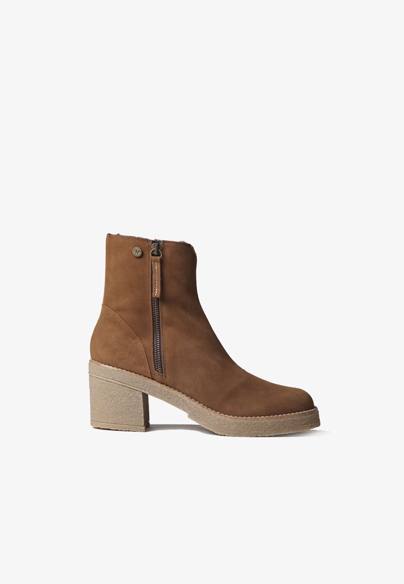 Botín de ante marrón hasta el tobillo con cierre de cremallera, punta redonda y un tacón grueso y texturizado. Decorado con una costura alrededor de la suela.