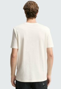 Weißes T-Shirt mit kurzen Ärmeln aus Baumwolle, das über einen klassischen Rundhalsausschnitt verfügt und eine glatte Textur sowie eine lockere Passform bietet.