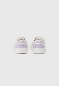 Sneakers din țesătură violetă cu tălpi din cauciuc alb și accente albe. Formă rotundă cu design cu șireturi, care evidențiază o suprafață texturată.