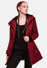 Parka aislante roja con forro interior negro, capucha ajustable, bolsillos con cremallera y puños acanalados. Presenta una textura suave y un diseño de largo hasta la rodilla.